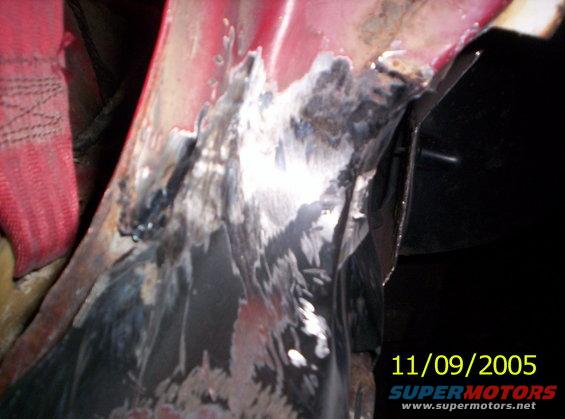 Rusted metal panel with welding marks and a red strap, close-up view