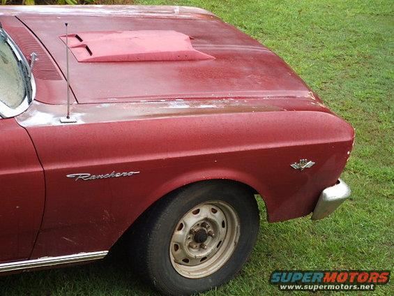 Red 1966 Ford Ranchero fender with chrome trim, steel wheel, and hood scoop. The vehicle shows rust and wear
