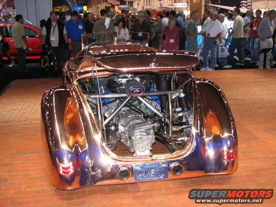 Copper-plated custom hot rod with exposed engine and transmission, viewed from the rear