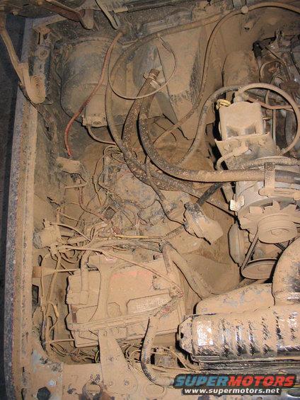 Mud-covered engine bay with exposed wiring and engine components. Visible text reads 'SUPERMOTORS.NET'