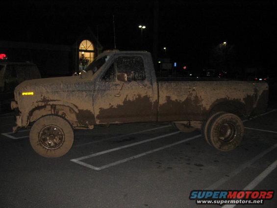 mud-covered pickup truck parked in a lot at night