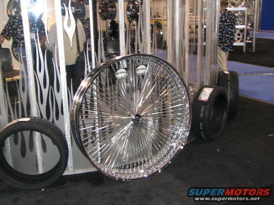 Chrome wire wheel with many spokes and two tires on display