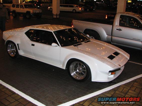 White sports car with aftermarket wheels parked next to a silver pickup truck