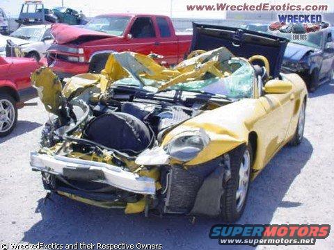 Heavily damaged yellow sports car with hood open, red pickup truck behind it
