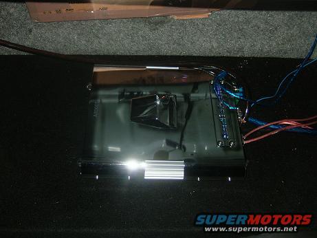 Car amplifier with blue and red wires connected, resting on dark carpet