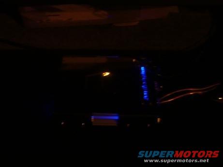 Car interior at night showing a blue-lit aftermarket stereo and wiring