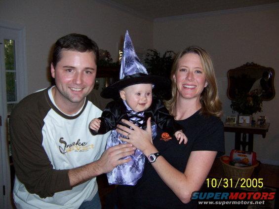 Family poses for a photo on Halloween, with a baby dressed as a witch