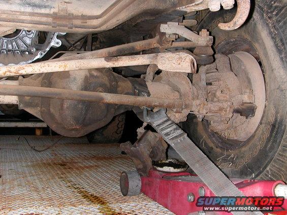 Undercarriage view of vehicle suspension and differential, with a red jack supporting it