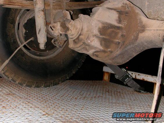 Close-up of a truck's rear axle, differential, leaf spring, and shock absorber