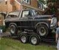 Black 1978 Ford Bronco on a trailer, viewed from the front-right