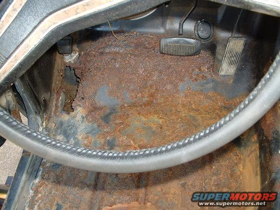 rusted floor pan with brake and clutch pedals visible