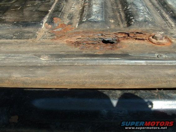 Rusted truck bed with hole and bolt