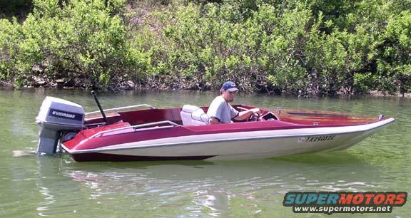 Red and white motorboat with an Evinrude outboard motor, a man at the helm, on a body of water