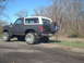 1986 Ford Bronco - Modified Ford Bronco from the 1980s, seen from the rear with a spare tire and lifted suspension.