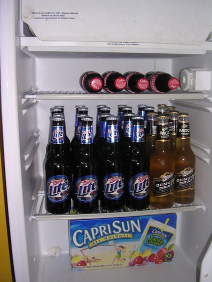 Refrigerator interior with Miller Lite, Miller Genuine Draft, and Coca-Cola bottles, plus a box of Capri Sun
