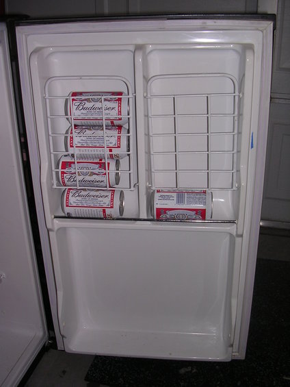 Refrigerator interior with wire shelves holding cans of Budweiser beer