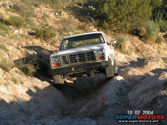 White 1980s Ford Bronco navigating rocky terrain