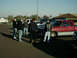 2002 Ford F-250 - A group of men stand around a red and white Dodge Ram pickup truck in a parking lot.