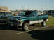 2002 Ford F-250 - A green and silver pickup truck is parked in a lot next to a dark SUV.