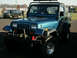 2002 Ford F-250 - A blue Jeep Wrangler is parked in a lot, with another SUV visible in the background.