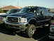 2002 Ford F-250 - A lifted 2002 Ford F-250 pickup truck is seen from the front-three-quarter view, parked alongside other vehicles.