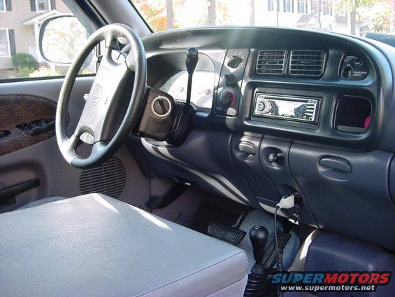 Pickup truck interior with steering wheel, dashboard, radio, and center console. Supermotors.net logo visible