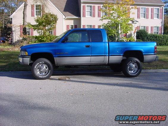 Blue and silver pickup truck side view. Text on tire reads "BAJA A/T"