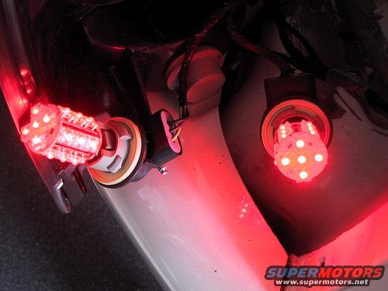 Close-up of two red LED tail light bulbs installed in a vehicle's rear light housing