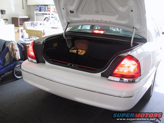 White 2003 Ford Crown Victoria sedan rear view with open trunk, chrome trim, and red taillights