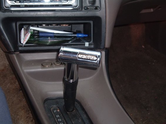 Aftermarket chrome shift knob with 'ractive' logo on center console, next to coin holder and radio