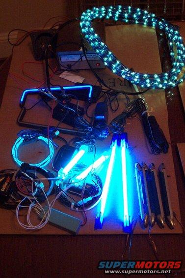 Various blue LED light strips, a coiled LED rope light, and wiring are laid out on a surface