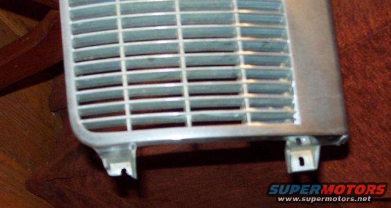 Close-up of a silver grille with horizontal slats and mounting tabs