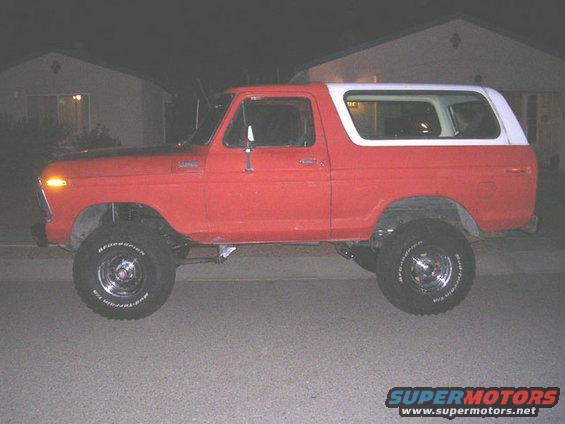 Red 1978 Ford Bronco parked outside a house at night