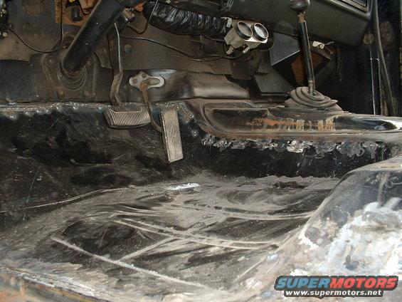 Interior floor and pedals of a vehicle, showing rust and wear