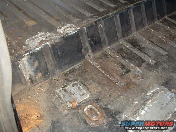 rusted floor pan with welded patches and some debris