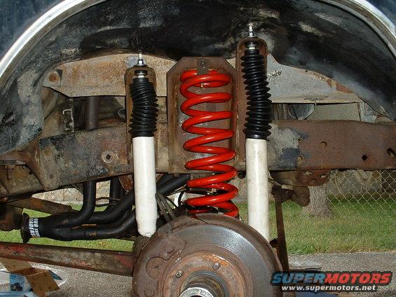 Close-up of red coil springs and white shock absorbers on a vehicle's suspension