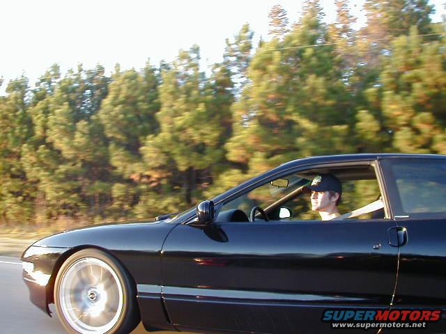 Black coupe with a driver, side view, motion blur on wheels