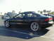 1994 Ford Probe - A black coupe with its hood up and aftermarket wheels is parked in a lot with other vehicles.