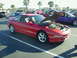 1994 Ford Probe - A red 1994 Ford Probe is parked with its hood open, revealing the engine bay. Other vehicles are visible in the background.