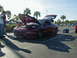 1994 Ford Probe - A group of people stand near a maroon Ford Probe with its hood and trunk open, parked in a lot with other vehicles.