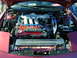 1994 Ford Probe - The engine bay of a red car displays a V6 engine with custom racing modifications and branding.