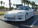 1994 Ford Probe - White coupe with aftermarket body kit, front-left view, parked in lot with palm trees.