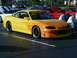 1994 Ford Probe - A yellow sports car with custom flame graphics is parked at an outdoor event.