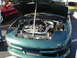 1994 Ford Probe - The engine bay of a green car is displayed with the hood up. Another car is visible in the background.