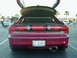 1994 Ford Probe - Rear view of a red 1994 Ford Probe GT, showing the trunk and gullwing doors open, with other vehicles in the background.