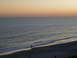 1994 Ford Probe - A lone figure walks along the shore as the sun sets over the ocean, creating a beach scene.