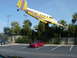 1994 Ford Probe - A red sports car is parked in a lot under a yellow airplane with colorful stripes.