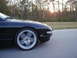 1994 Ford Probe - A black sports car is captured in motion on a highway as the sun sets through the trees.