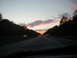 1994 Ford Probe - Cars drive on a highway during a colorful sunset with trees on either side.