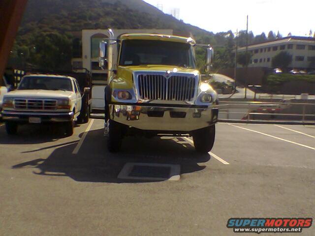 Yellow semi-truck parked next to a white pickup truck